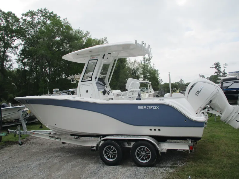 Slide: The Image of 2025 Sea Fox 228 Commander boat on trailer, white and blue design, parked outdoors. - 5