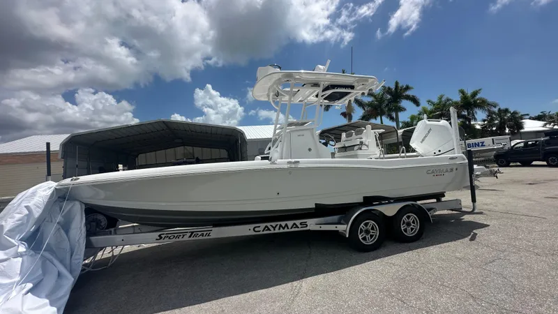 The Image of 2025 Caymas 26 HB boat on trailer under cloudy sky, parked near palm trees. - 1