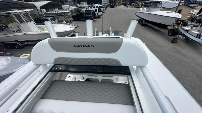 Slide: The Image of 2025 Caymas 26 HB boat with cushioned seating, docked among other boats. - 5