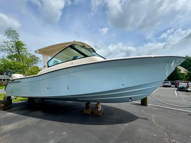 The Image of 2025 Grady-White 345 boat on display in a parking lot under a cloudy sky. - 1