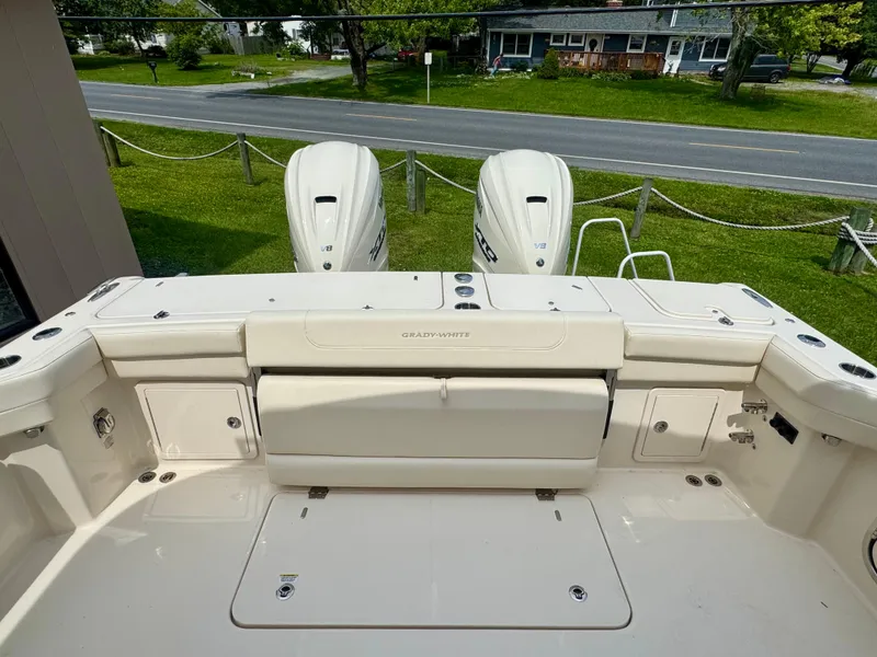 Slide: The Image of 2025 Grady-White 345 boat deck with dual outboard motors, parked near a road. - 17