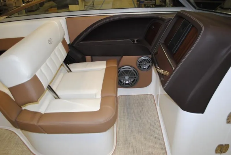 Slide: The Image of 2016 Cobalt 296 boat interior with brown and white seating, speakers, and carpeted flooring. - 18