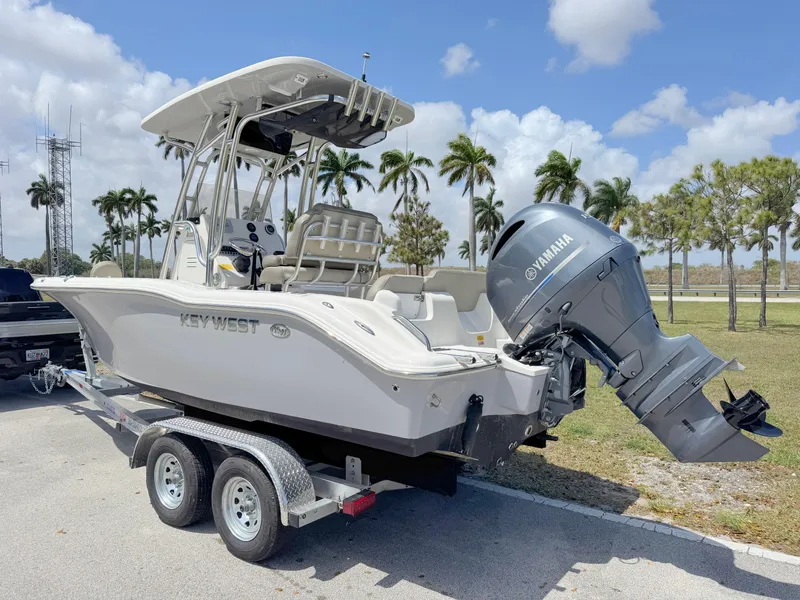 Slide: The Image of 2022 Key West 219 FS boat on trailer with Yamaha outboard, parked near palm trees. - 2