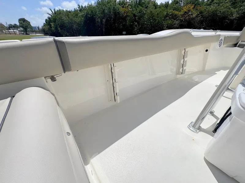 Slide: The Image of 2022 Key West 219 FS boat interior with white seating and railing, surrounded by greenery. - 25
