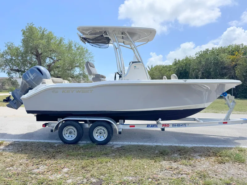Slide: The Image of 2022 Key West 219 FS boat on trailer, parked outdoors under a cloudy sky. - 5
