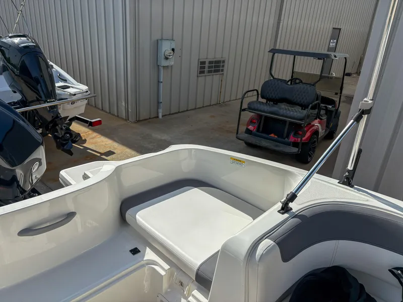 Slide: The Image of 2019 Bayliner Element E16 boat interior with seating, parked near a golf cart. - 8