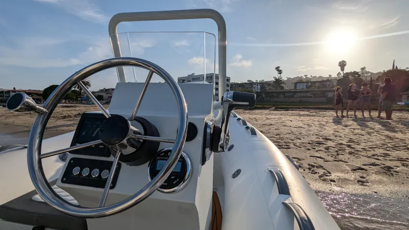Slide: The Image of 2025 Tide Craft Catalina 13 DEMO Boat on sandy beach at sunset, steering wheel in focus. - 5