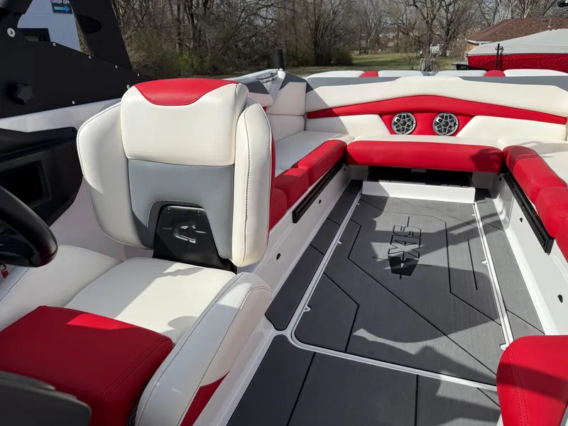 Slide: The Image of 2020 Axis A24 boat interior with red and white seating, gray flooring, and speakers. - 18