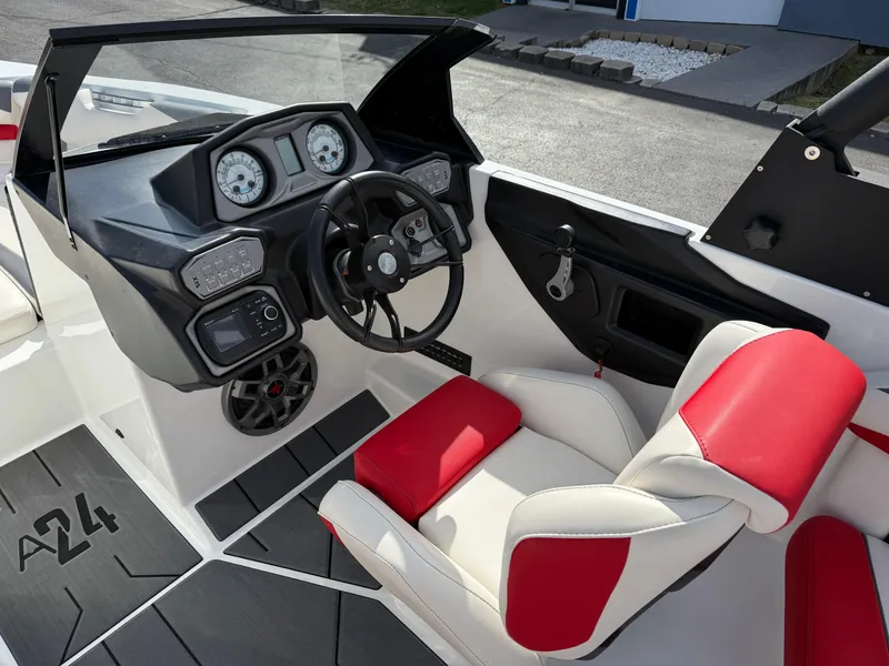 Slide: The Image of 2020 Axis A24 boat interior with red and white seating, modern dashboard, and steering wheel. - 24