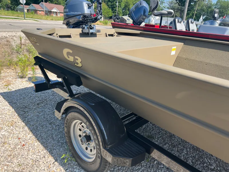 Slide: The Image of 2025 G3 1652 VBW boat on trailer, parked on gravel, with motor attached. - 4