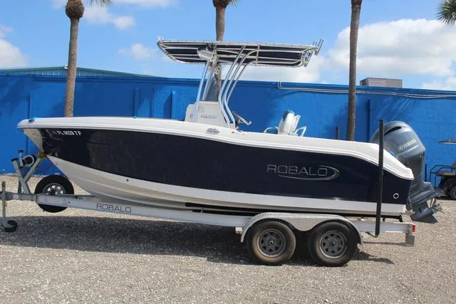 Slide: The Image of 2022 Robalo R200 boat on trailer, parked outdoors with blue building background. - 7