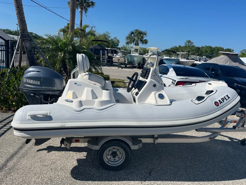 Slide: The Image of 2014 Apex A-11 Tender boat on trailer with Yamaha engine, parked outdoors. - 1