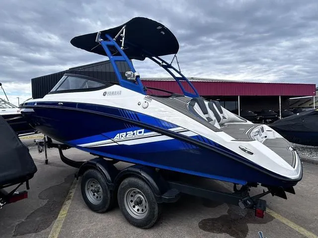 Slide: The Image of 2020 Yamaha AR210 boat on trailer, blue and white design, parked outdoors under cloudy sky. - 6