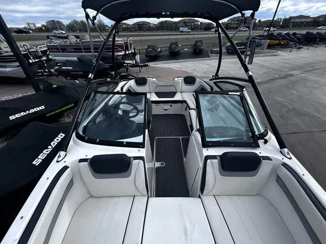 Slide: The Image of 2015 Yamaha Boats AR192 interior with seating and windshield, docked near Sea-Doo watercraft. - 13
