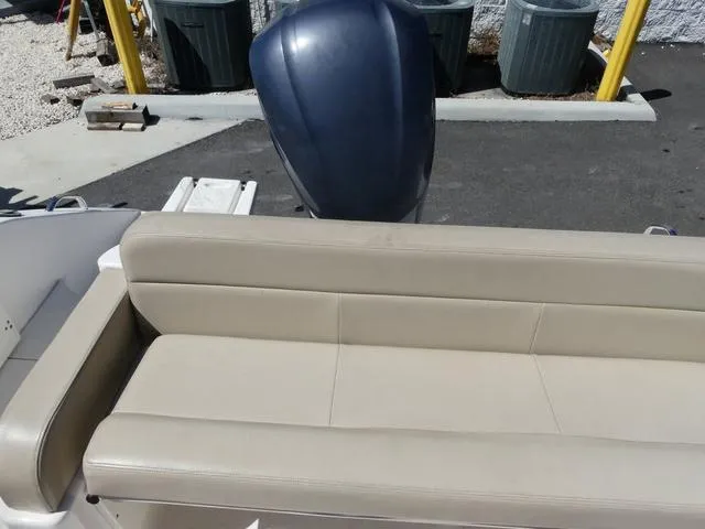 Slide: The Image of 2015 Pursuit Boats DC 235 with beige seating and outboard motor in parking area. - 16