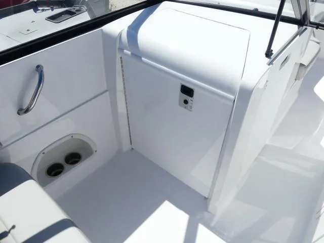 Slide: The Image of 2025 Hurricane SunDeck 235 OB boat interior with white seating and storage compartment. - 12