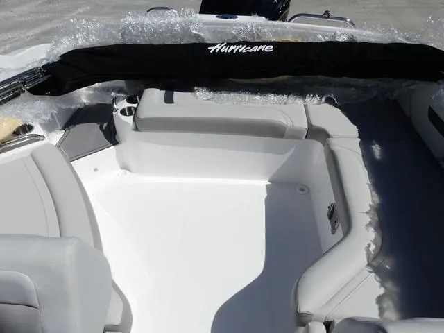 Slide: The Image of 2025 Hurricane SunDeck 235 OB boat interior with white seating and protective cover. - 13