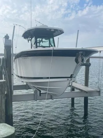 Slide: The Image of 2022 Blackfin 272CC boat on lift by the water under a cloudy sky. - 1