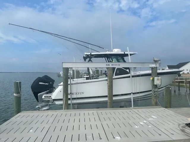 Slide: The Image of 2022 Blackfin 272CC boat docked at a marina under a cloudy sky. - 2