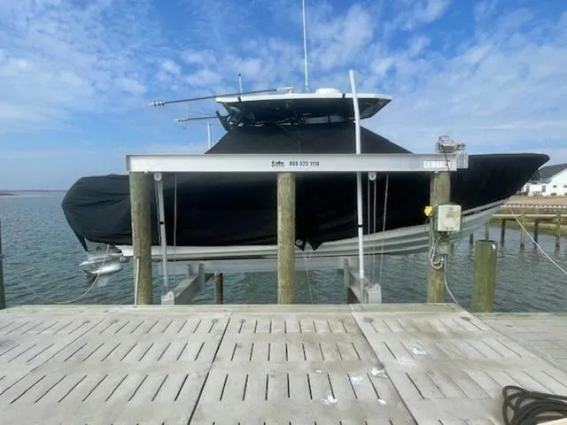 Slide: The Image of 2022 Blackfin 272CC boat on lift, covered, dockside with blue sky background. - 3