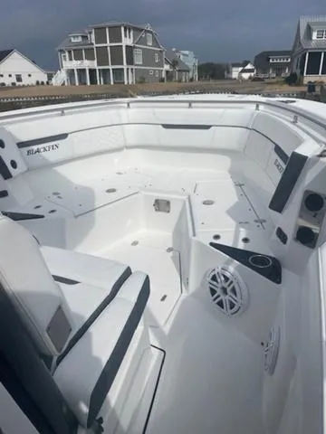 Slide: The Image of 2022 Blackfin 272CC boat interior with seating and speakers, docked near coastal homes. - 6