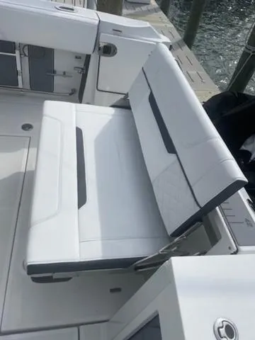 Slide: The Image of 2022 Blackfin 272CC boat with white cushioned seating, docked by the water. - 7