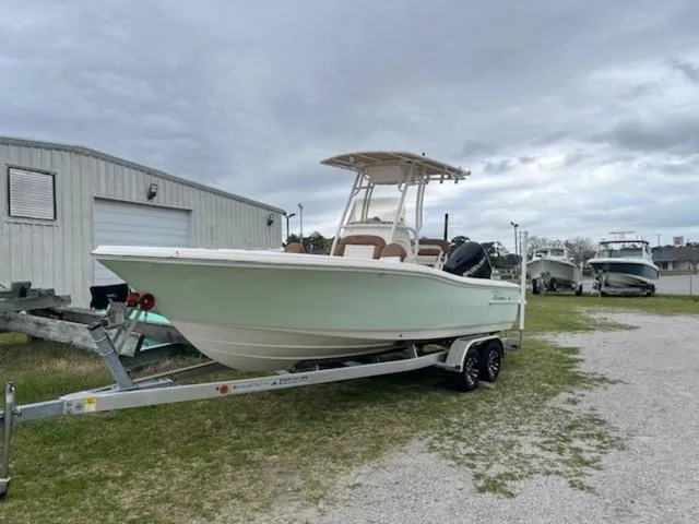 Slide: The Image of 2023 Pioneer 220 Bay Sport boat on trailer, parked outdoors near storage building. - 1