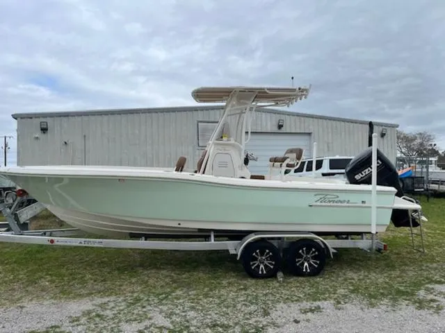 Slide: The Image of 2023 Pioneer 220 Bay Sport boat on trailer, parked outdoors near a building. - 2