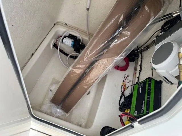 Slide: The Image of 2023 Pioneer 220 Bay Sport boat storage compartment with equipment and wiring. - 9