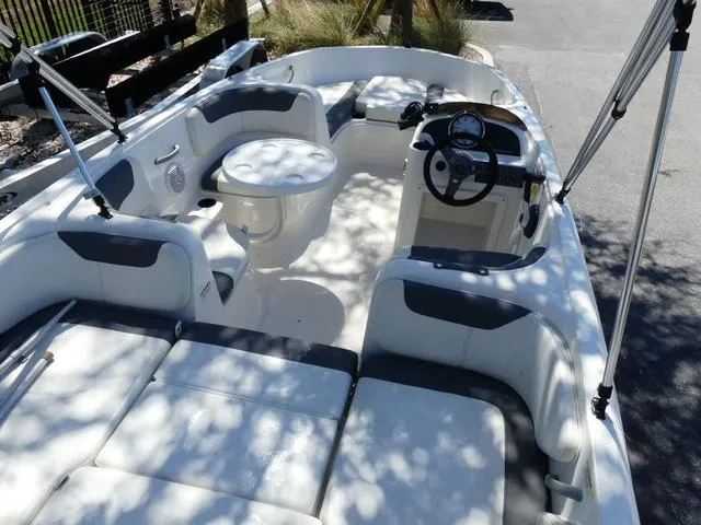 Slide: The Image of 2019 Bayliner Element E18 boat interior with seating, steering wheel, and table. - 3