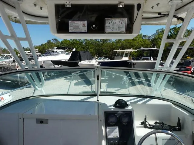 Slide: The Image of 2002 Seaswirl Striper 2301 boat cockpit with steering wheel and dashboard, docked among other boats. - 13