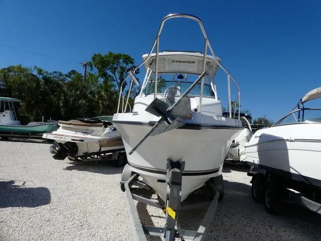 Slide: The Image of 2002 Seaswirl Striper 2301 boat on trailer, parked outdoors under clear blue sky. - 2