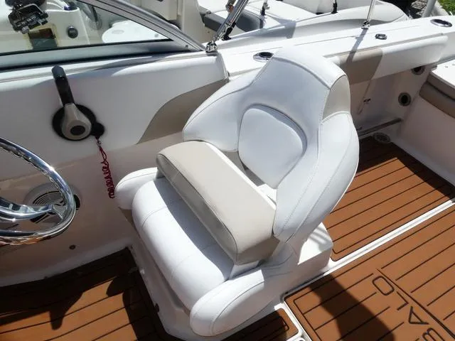 Slide: The Image of 2019 Robalo R207 boat interior with white and beige seating, brown deck flooring. - 10