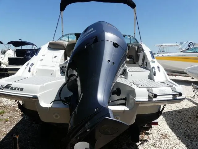 Slide: The Image of 2018 Crownline E23 XS boat with outboard motor, docked on gravel under clear sky. - 6