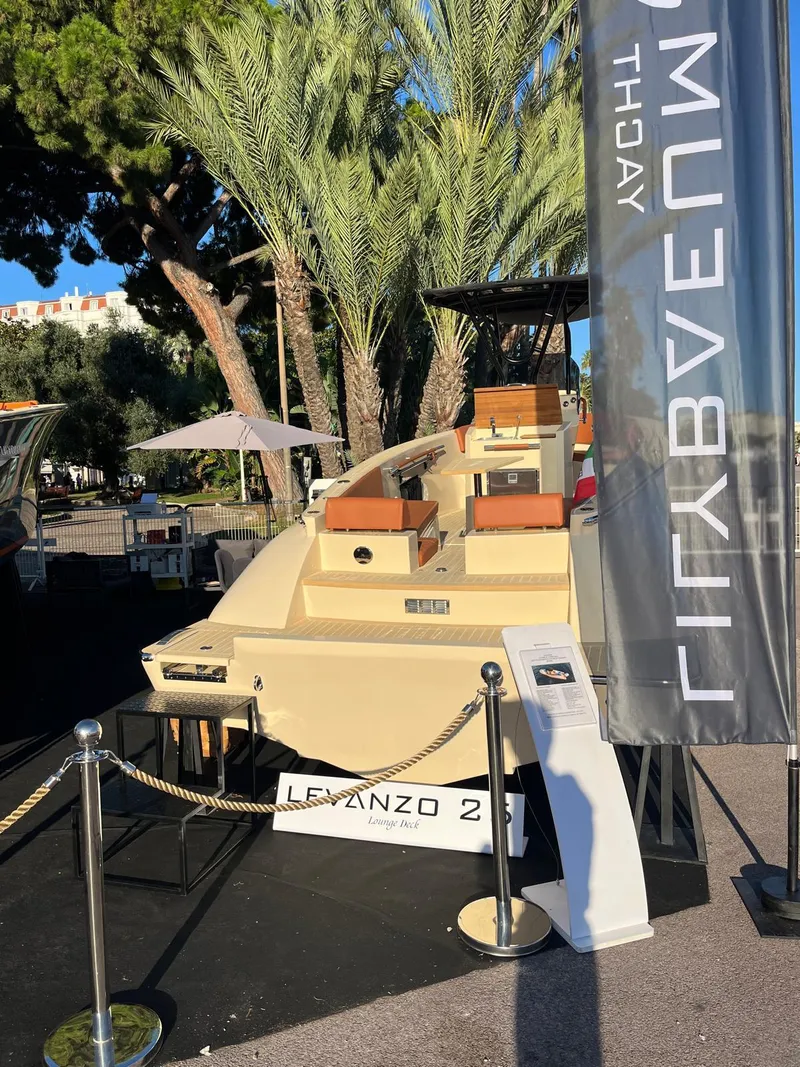 Slide: The Image of 2025 Lilybaeum Levanzo 25 Lounge Deck boat displayed outdoors with palm trees and promotional banner. - 29