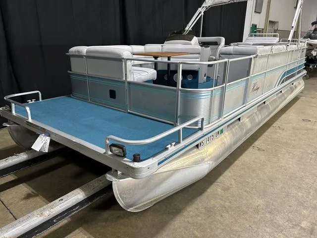 Slide: The Image of 1994 Harris-Kayot Heritage 2400 pontoon boat with blue carpet and white seating, indoors. - 5