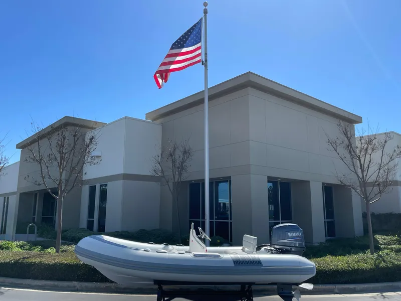 Slide: The Image of 2007 Novurania Deluxe 400 boat displayed outside building with American flag. - 1