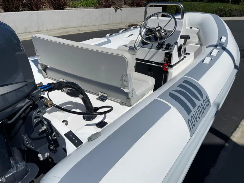 Slide: The Image of 2007 Novurania Deluxe 400 boat with steering console and seating, docked outdoors. - 10