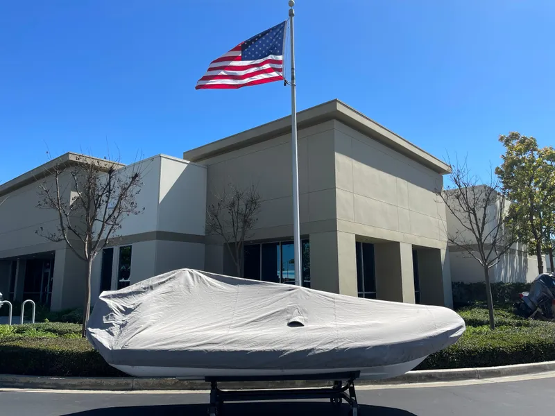 Slide: The Image of 2007 Novurania Deluxe 400 boat covered, parked near building with American flag. - 19