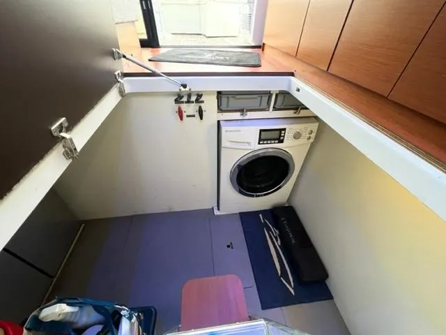 Slide: The Image of Laundry area on a 2014 Jeanneau NC14 boat with a washing machine and storage space. - 13