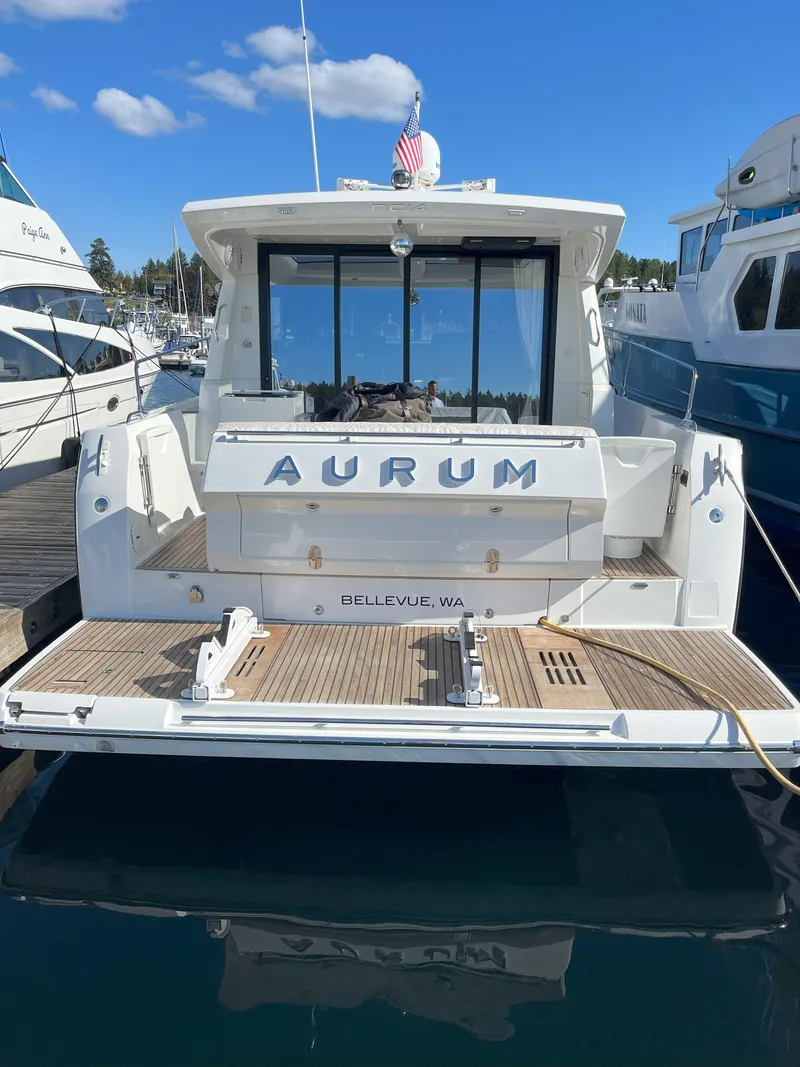 Slide: The Image of 2014 Jeanneau NC14 yacht docked, rear view with "AURUM" name, clear sky background. - 9