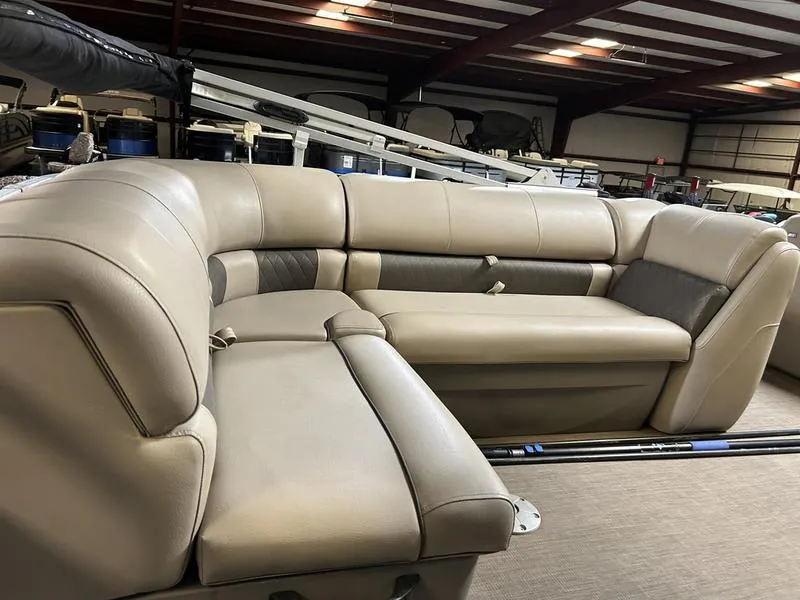 Slide: The Image of 2022 Sun Tracker PARTY BARGE® 20 DLX interior with beige seating in a warehouse setting. - 13
