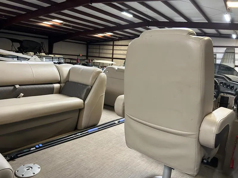 Slide: The Image of 2022 Sun Tracker PARTY BARGE® 20 DLX interior with beige seating in a warehouse setting. - 14