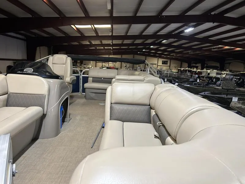 Slide: The Image of 2022 Sun Tracker PARTY BARGE® 20 DLX interior with beige seating in a showroom. - 5