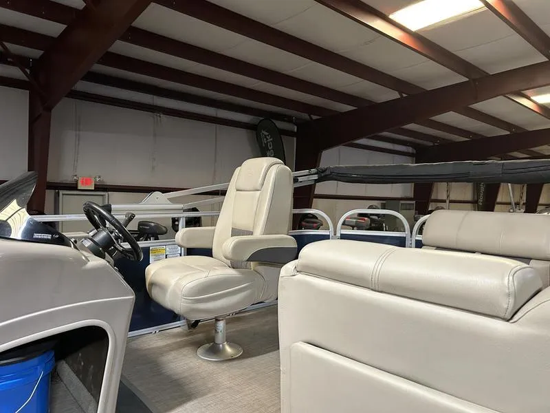 Slide: The Image of 2022 Sun Tracker PARTY BARGE® 20 DLX interior with beige seating in a warehouse. - 7
