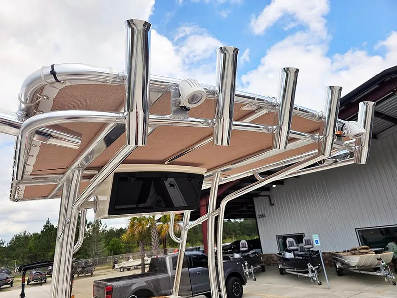 Slide: The Image of 2025 Pioneer 202 Islander boat with T-top rod holders and electronics, parked outdoors. - 13