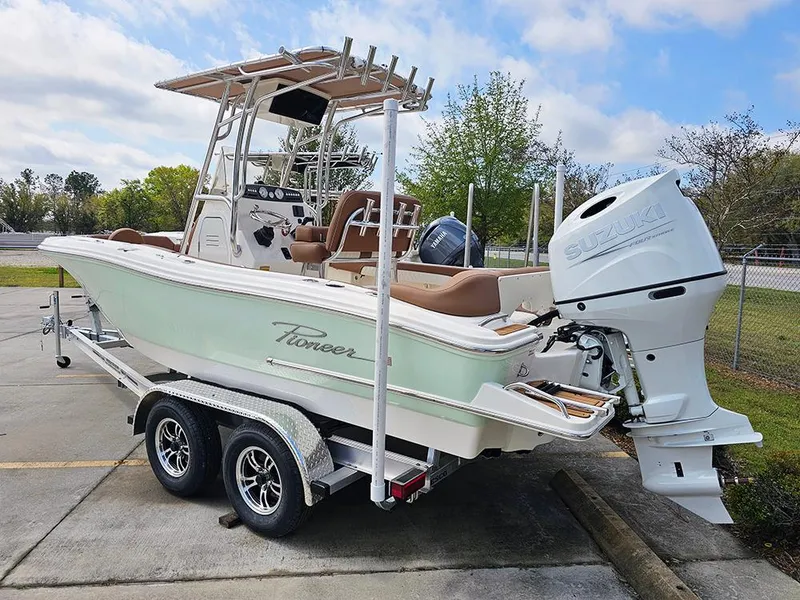 Slide: The Image of 2025 Pioneer 202 Islander boat on trailer with Suzuki outboard motor, parked outdoors. - 3