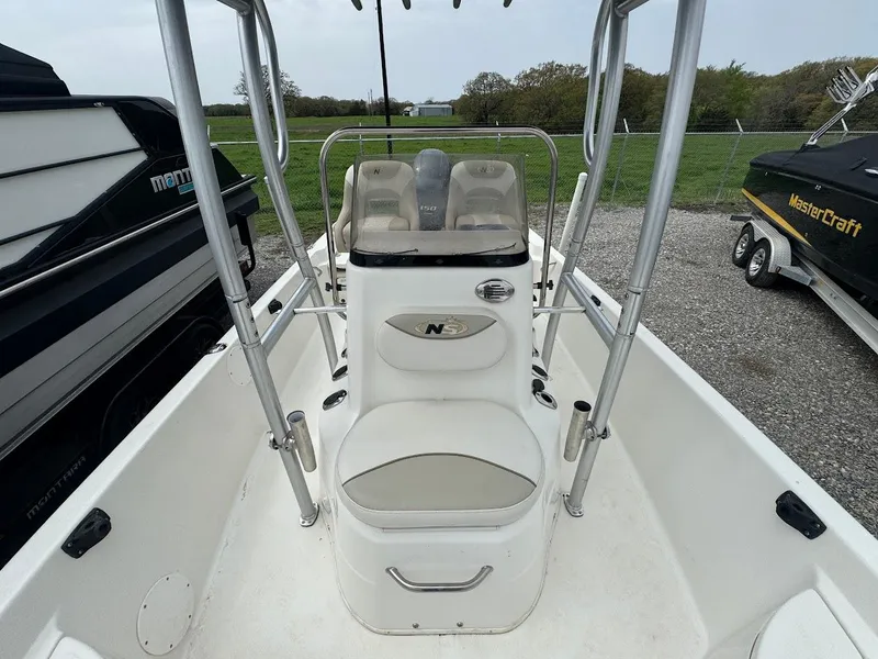 Slide: The Image of 2015 NauticStar 2110 Sport boat interior with seating and console, parked outdoors. - 4