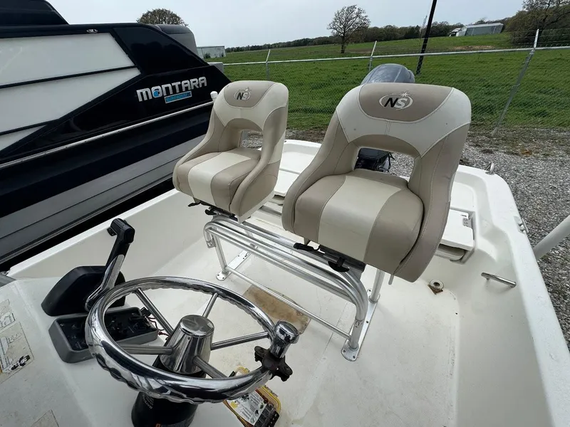 Slide: The Image of 2015 NauticStar 2110 Sport boat with dual seats and steering wheel, parked outdoors. - 5