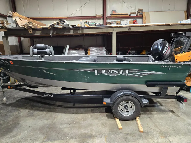 Slide: The Image of 2014 Lund 1650 Rebel Tiller boat in a warehouse setting. - 1